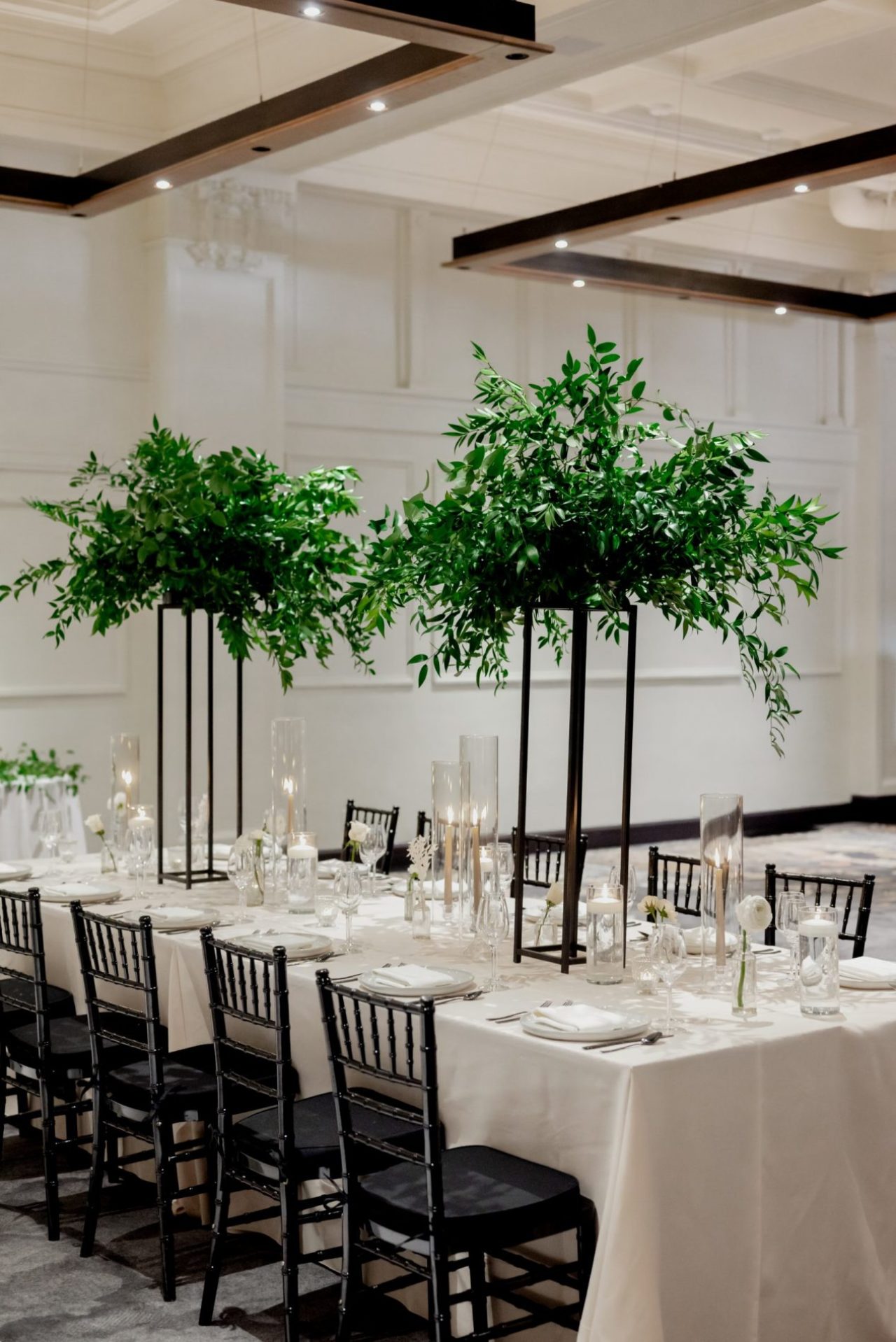 Tall leafy centerpieces on a table set in a Des Moines wedding venue
