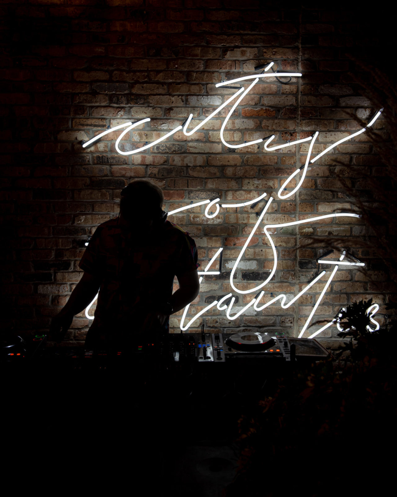 DJ silhouetted by a neon sign at our patio bar in Des Moines