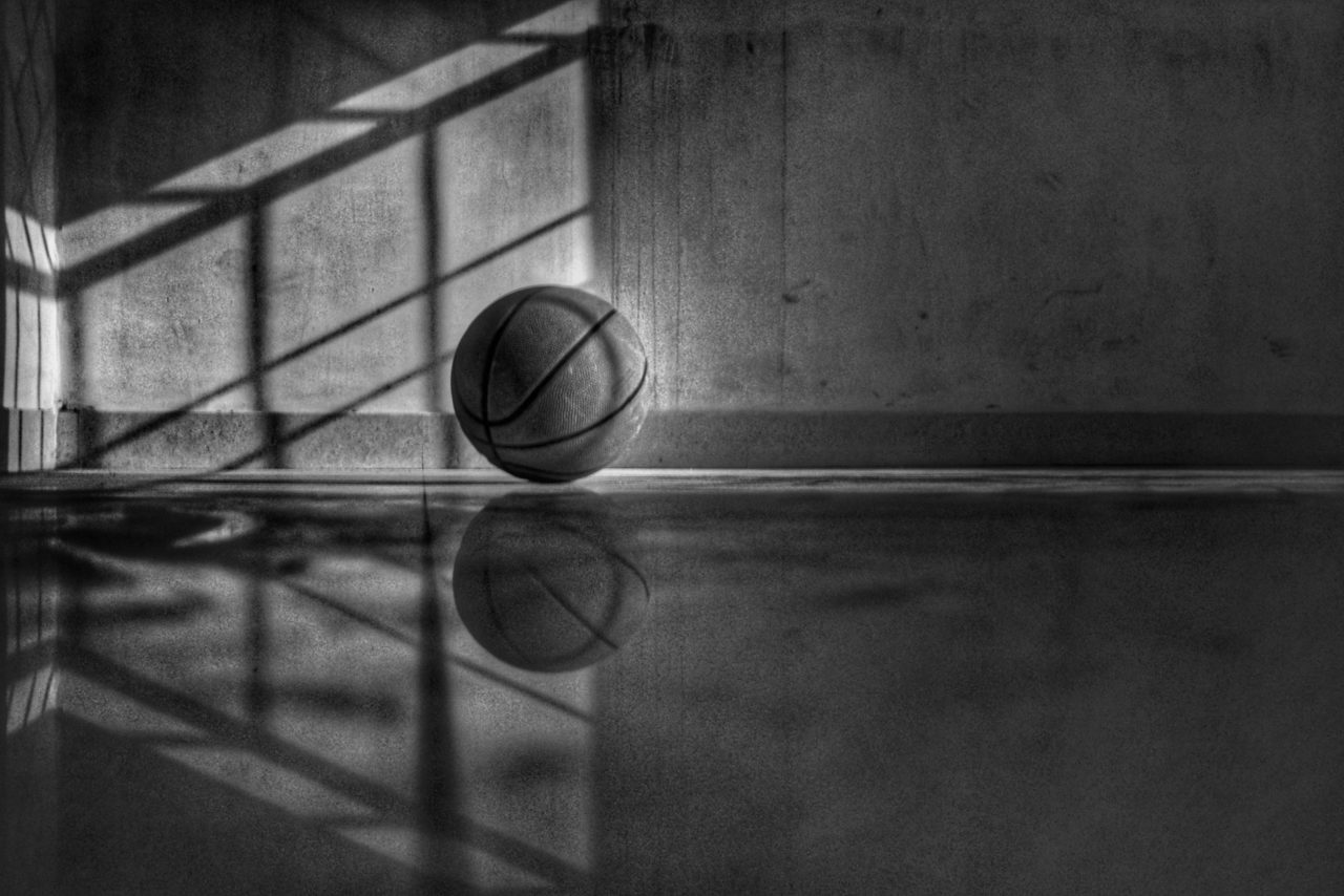 Dramatically lit black and white image of a basketball on the floor