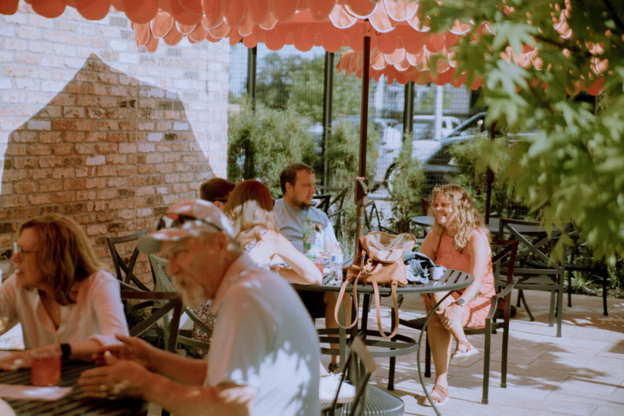 People enjoying a meal under shaded tables at our patio bar in Des Moines